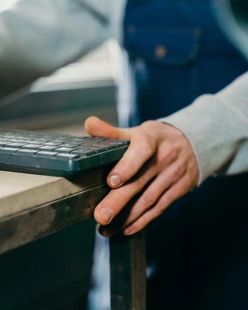 Main d'artisan posée à côté d'un clavier — la rencontre du métier et du numérique